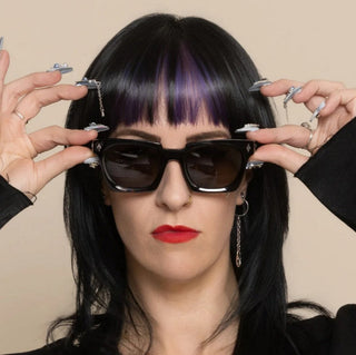 Woman wearing dark sunglasses with hands adjusting sunglasses