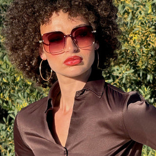 Woman wearing sunglasses and a brown outfit with a blurred background
