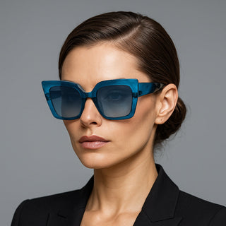 Woman wearing blue sunglasses against a gray background