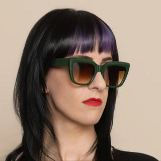Person wearing green sunglasses with a neutral background