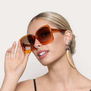 Woman wearing orange sunglasses against a plain background