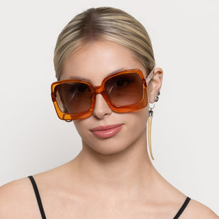 Woman wearing large orange sunglasses with a neutral background
