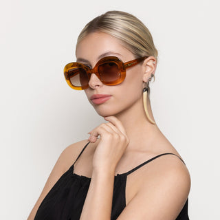Woman wearing large orange sunglasses against a plain background