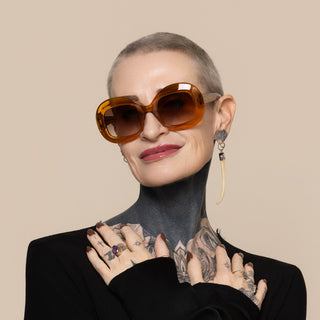 Woman wearing orange sunglasses and a black outfit with a neutral background