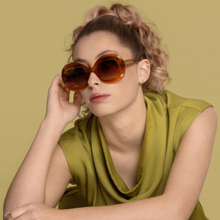 Woman wearing sunglasses and a green top against a yellow background