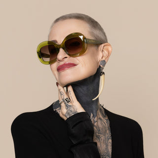 Person wearing large green sunglasses with a neutral background