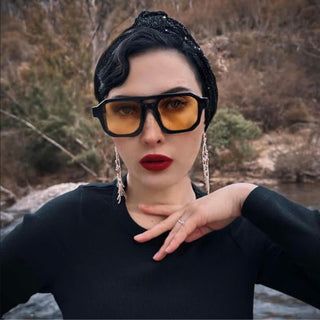 Woman wearing yellow lense sunglasses with a blurred natural background