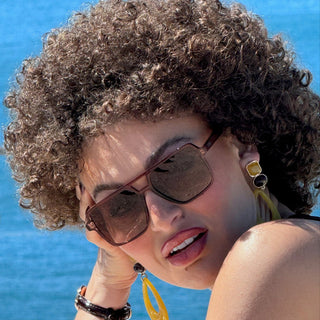 Woman with brown sunglasses and ocean in background