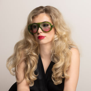 Woman wearing large green sunglasses with a neutral background