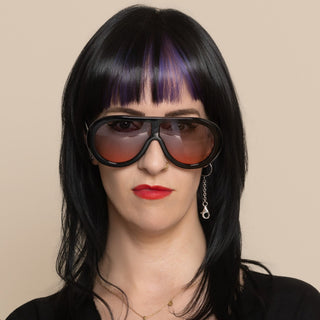 Woman wearing large sunglasses and a black outfit against a beige background