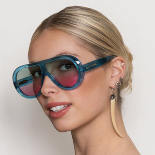 Woman wearing blue sunglasses with a neutral background