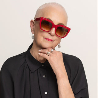 Person wearing red sunglasses and a black shirt against a plain background