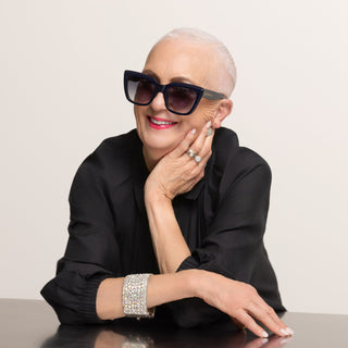 Woman wearing sunglasses and a black outfit with a neutral background