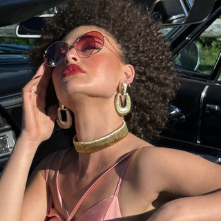 women in rose coloured sunglasses and pink dress in car