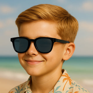 Young boy wearing sunglasses and a palm tree shirt on a beach