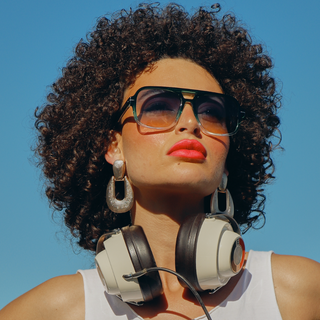 Woman with sunglasses and headphones against a clear blue sky