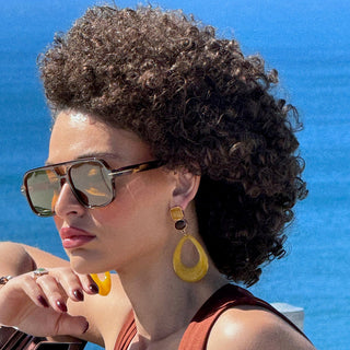 Woman with sunglasses and curly hair against a blue background