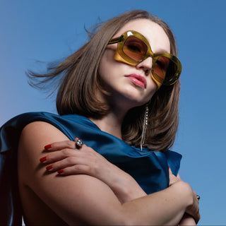 Woman wearing green sunglasses against a clear blue sky