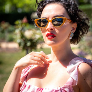 Woman wearing cateye sunglasses and a pink dress in an outdoor setting