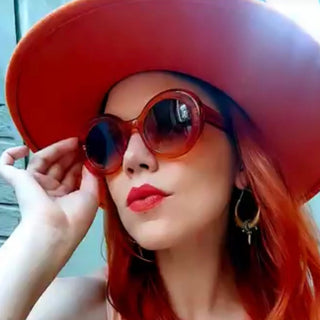 Woman wearing a red hat and sunglasses with a blurred background