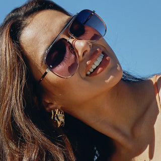 Woman wearing aviator sunglasses with a clear blue sky background