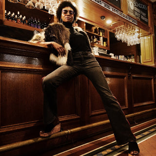 Person with afro and aviators at a bar counter in a dimly lit pub