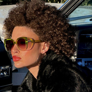 woman with curly hair and green sunglasses