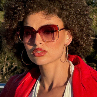 Person wearing sunglasses and a red jacket with a blurred background
