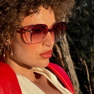 Person wearing rose coloured sunglasses with a scenic background