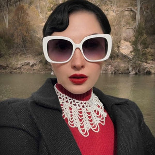 Person wearing oversized white sunglasses with a scenic background