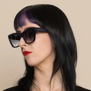 Woman wearing blue-black sunglasses with a beige background